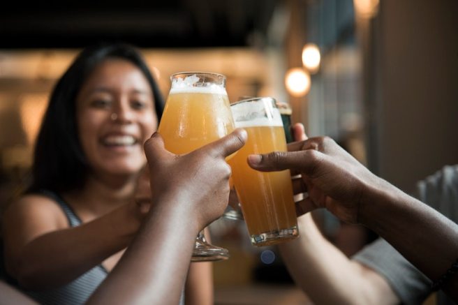 Three people drinking beer and toasting